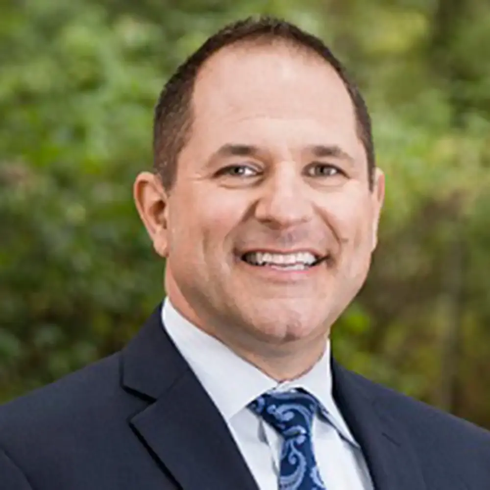 Clint Mahlman headshot, in a navy suit and tie