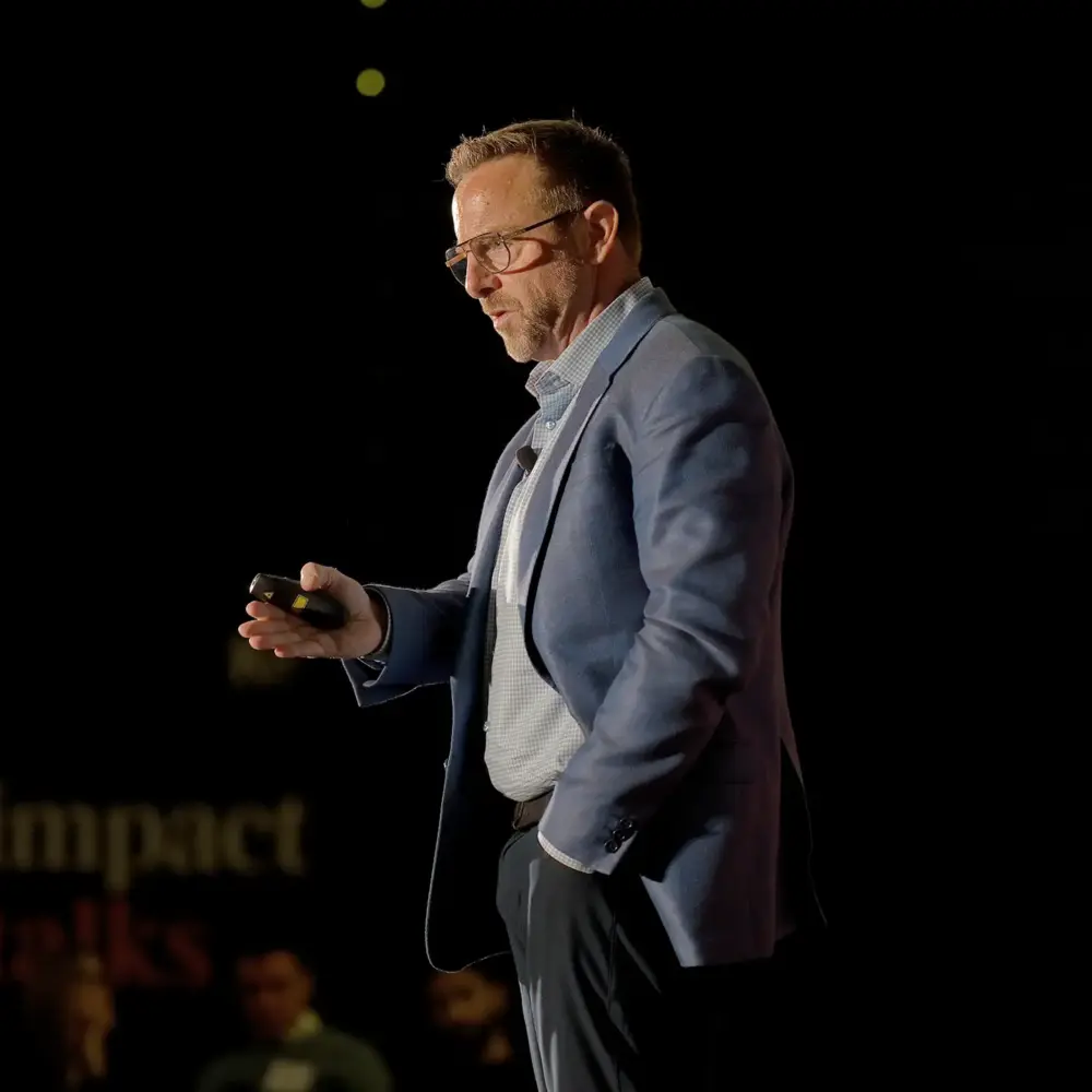 Nick Kindler in a blue blazer mid-talk on a dark stage