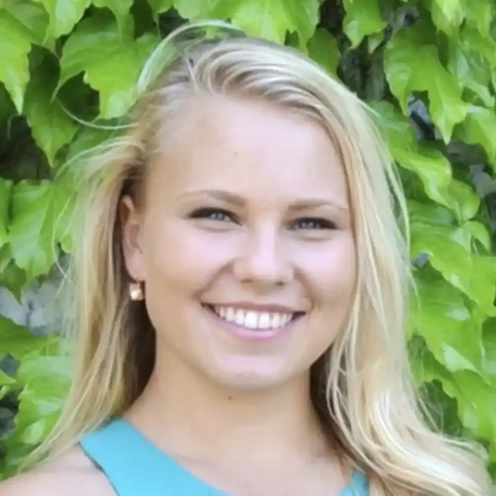 Michelle Woitowich headshot, smiling in front of green ivy