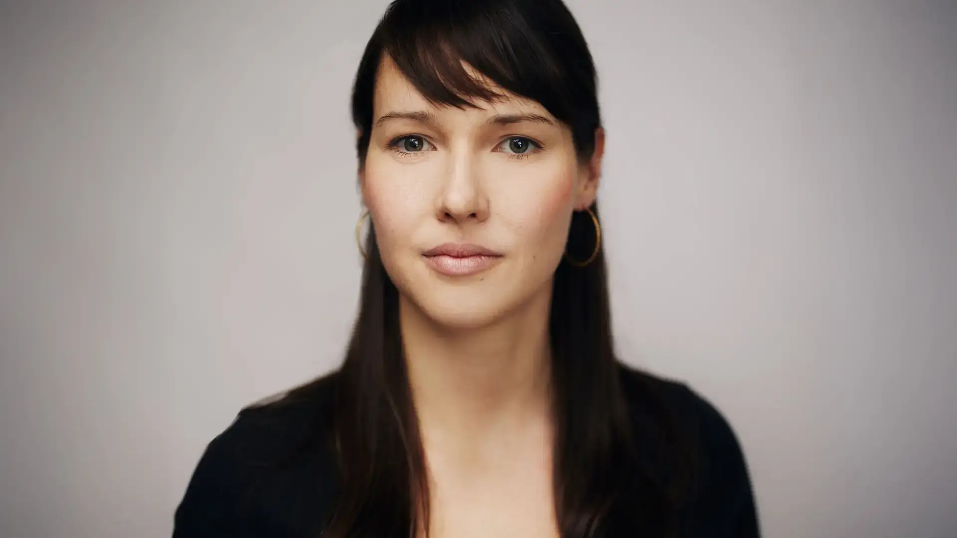 Stephanie Damgaard headshot, in black against a neutral backdrop