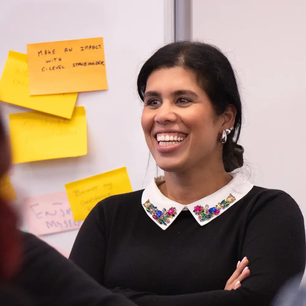 Smiling workshop participant in front of sticky notes about making an impact with C-level stakeholders